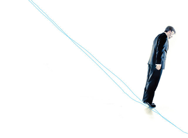 Man in suit standing on string on downward diagonal