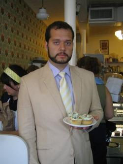 Jesse Brown holds plate of cupcakes wearing a suit