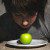 Boy looking at a green apple