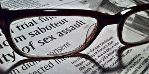 Eye glasses on news paper page highlighting words "sex assault"