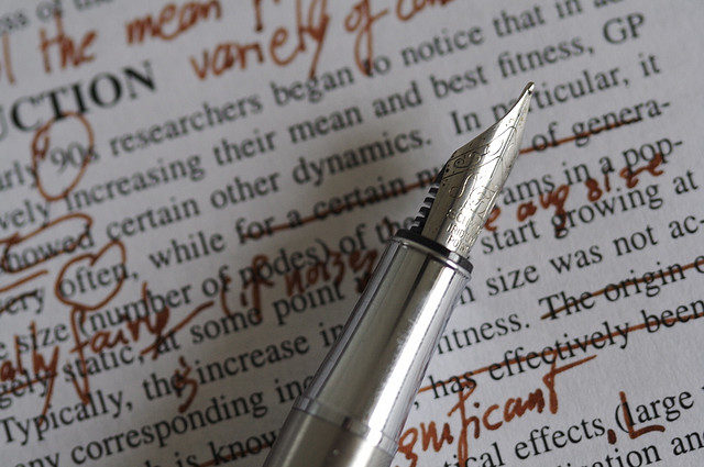Ink pen making corrections on typed paper