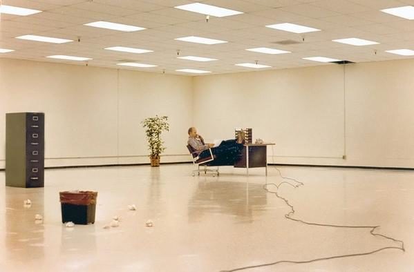 Man in large empty office room at his desk