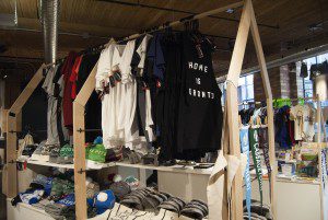 T-shirts of different colours hang in the Spacing Store Toronto. The first one says "Home is Toronto" on the front.