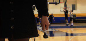 Hand holding a microphone in front of a basketball court