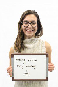 Woman holds whiteboard "Reading fiction every morning and night"