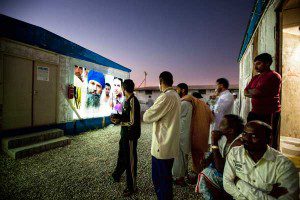 Photos projected on Dubai trailer homes surrounding by onlookers