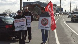 3 strikes from Chronicle Herald with signs and a flag