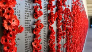 Memorial lists names of lost soldiers and it adorned with poppies