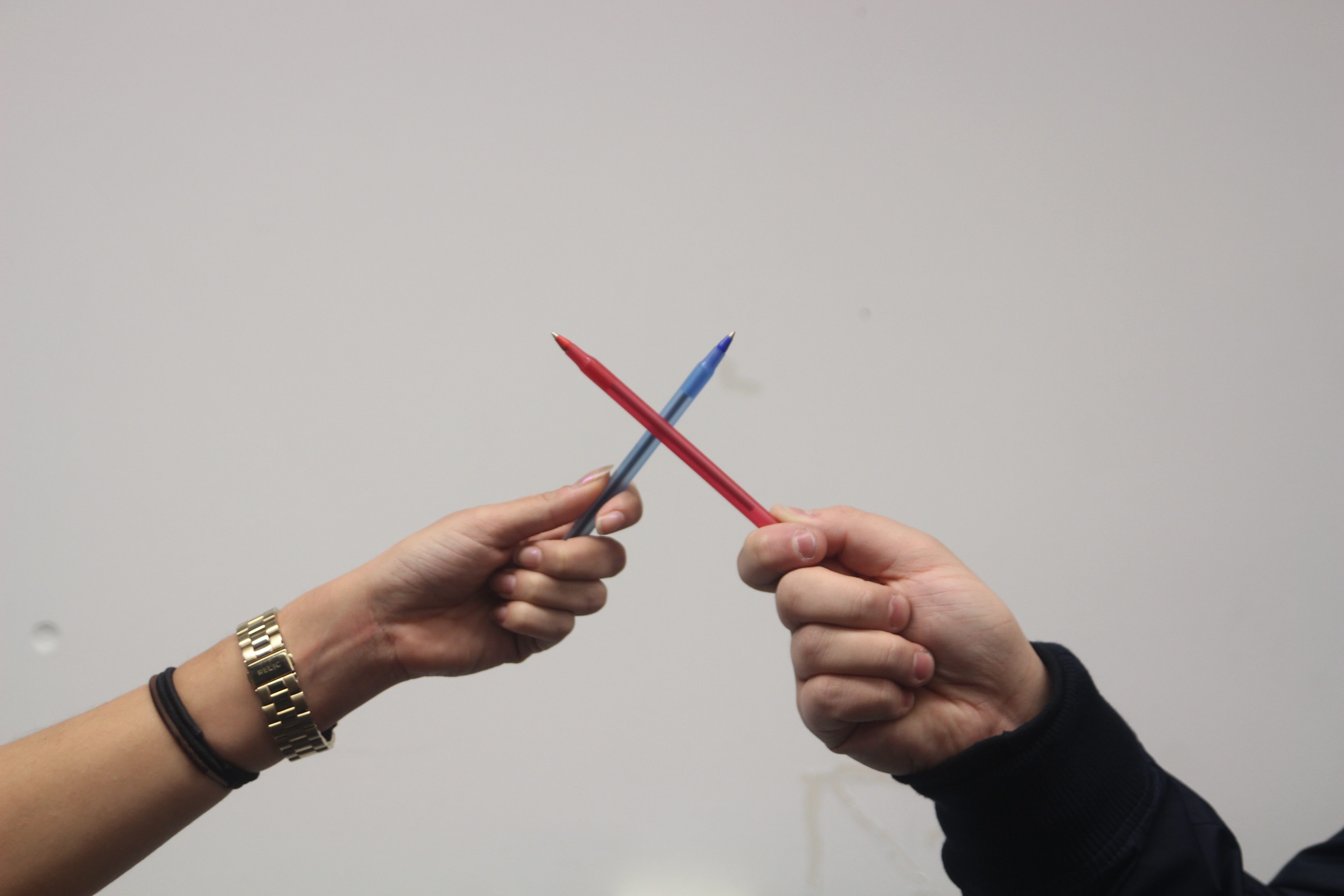 Two pens being held in the shape of an x