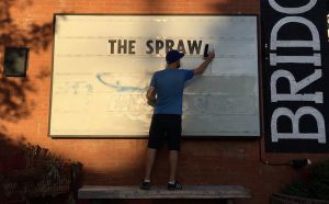 Jeremy Klaszus places letters spelling "The Sprawl" on a billboard