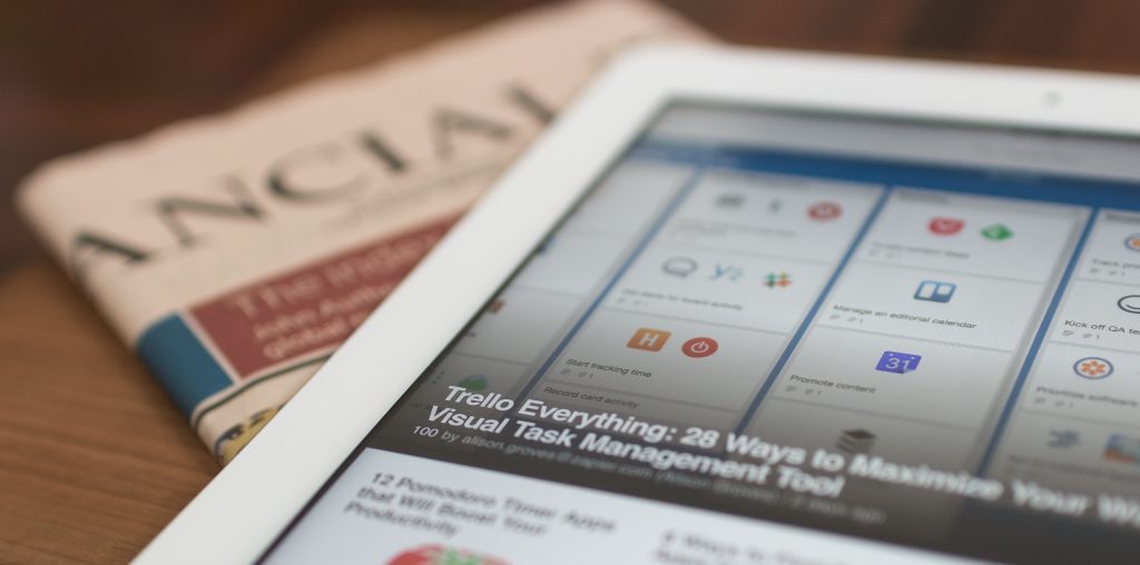An iPad sits on top of a copy of the newspaper, with a listicle open.