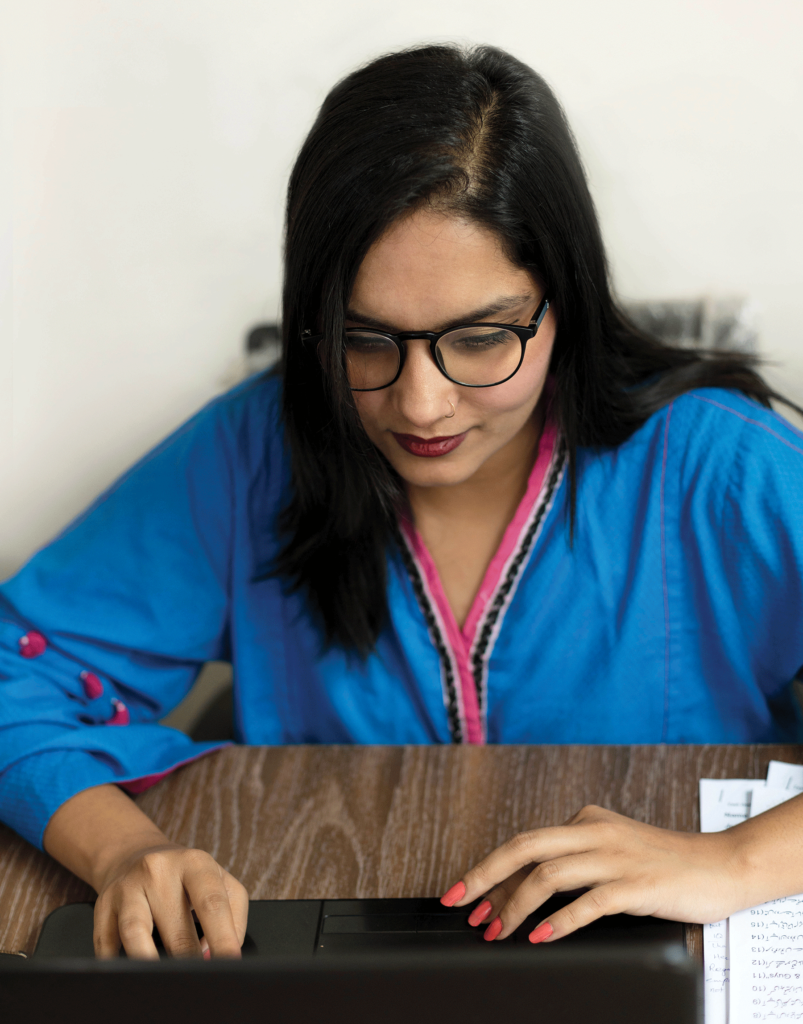 Laiba Zainab sits typing on a laptop