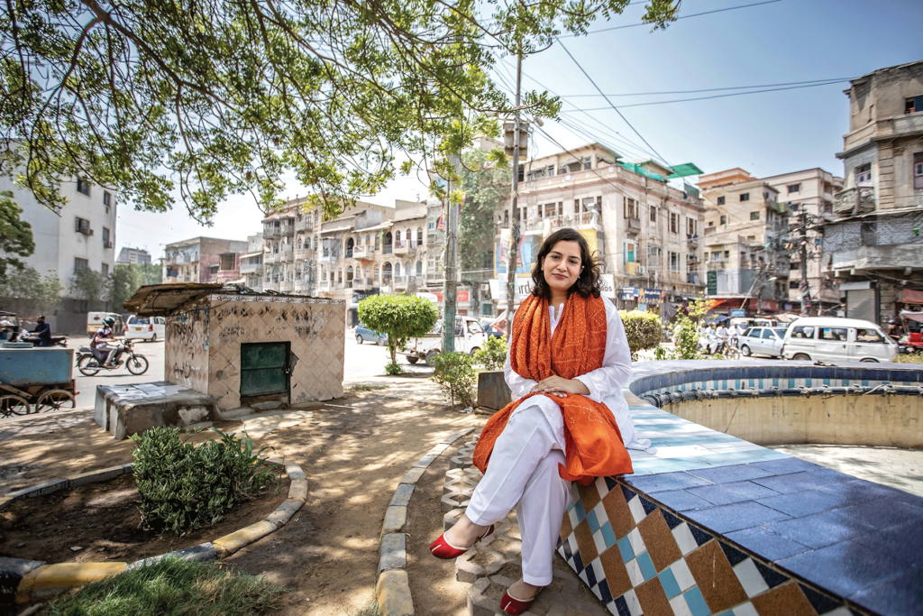 Sanam Maher sits on the ledge of an empty fountain in Pakistan