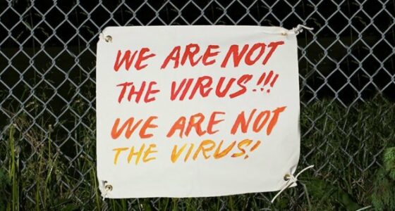 Sign on a fence that says we are not the virus, we are not the virus.